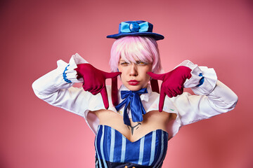 good looking sexy woman with red gloves and blue hat showing crying gesture on pink backdrop