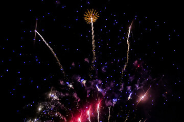 Large fireworks fly up in the black night sky