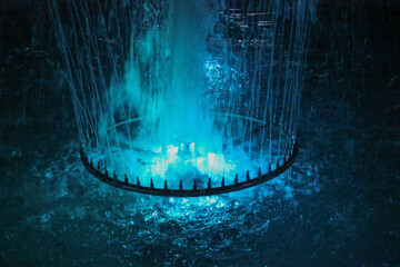 The fountain glows blue with lots of splashes	
