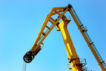 Yellow harbor crane against a clear turquoise sky	
