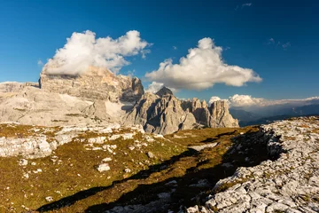 Rolgordijnen Rocky footpaths below the monumental peak of Tre Cime with the cloudy blue sky © Simona_Mach