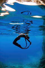 free diver girl doing acrobatic stunts underwater.