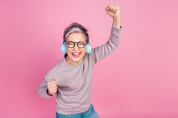 Photo of overjoyed glad retired woman raise hands have fun dance chill feel young isolated on pink...
