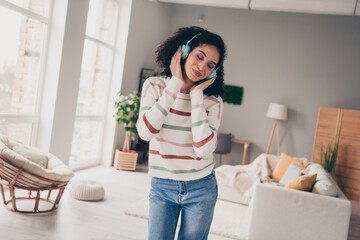Photo of cute good mood lady dressed striped pullover enjoying songs earphones indoors apartment room