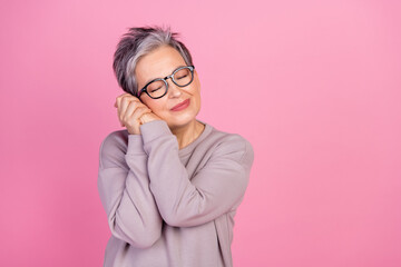 Photo of dreamy lovely senior woman wear stylish clothes enjoying comfy warm sweater isolated on pink color background