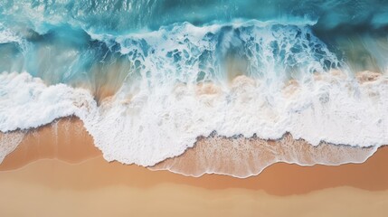 Aerial view of the ocean waves crashing against brown sand, creating dynamic patterns and textures.
