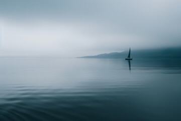 Sailboat in calm water with misty fog background