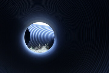 Black pipe swirl ring. Tunnel of prefabricated industrial plastic pipes stored outdoors in pipe inside view with copy space with selective focus.