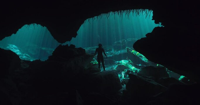 Diver standing and walking on a submerged rock in a cave