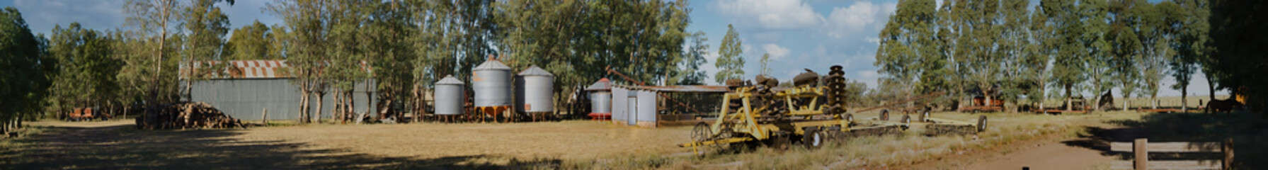 Silos, Logs, and Rusty Machinery in a Rural Panorama