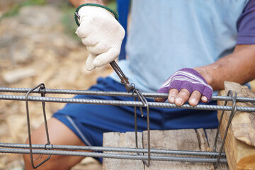 Closeup construction worker ties  iron wire on metal bar reinforcement of concrete work. Concept,...