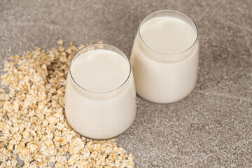 Oat milk in glasses on a gray concrete background. Alternative plant milk