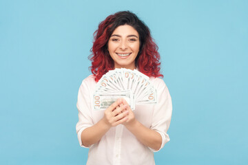 Portrait of rich smiling woman with fancy red hair holding big fan of euro banknotes, earning...
