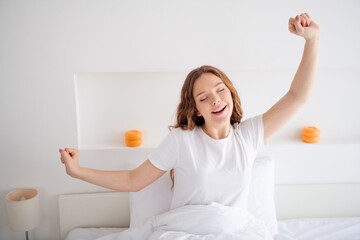 Portrait of attractive carefree girl closed eyes sit comfy bed stretch arms yawn free time bedroom...