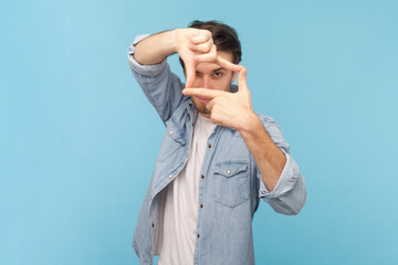 Portrait of focused unshaven attractive man photographer making frame with both hands, having...
