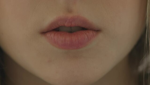 Unrecognizable girl moves her lips close-up. Female lips says something or sings a song