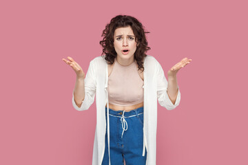 Portrait of angry beautiful young adult woman with curly hair wearing casual style outfit raised...