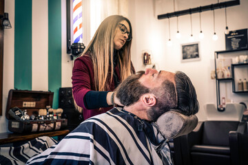 Woman skilled stylist at work in a trendy barber shop. Careful attention to detail ensures a perfect grooming experience for the customer.