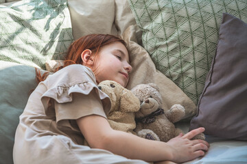 beautiful cute little girl sleeping peacefully and hugging her stuffed toys in bed