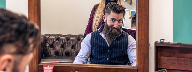 Satisfied customer with styled beard in barbershop mirror. The reflection captures a moment of...