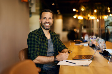 Portrait of a Smiling Businessman posing for the camera while working in the co-working space.