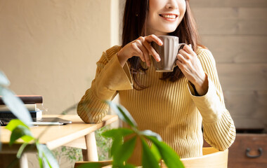 飲み物を飲みながらデスクワークをする笑顔の女性