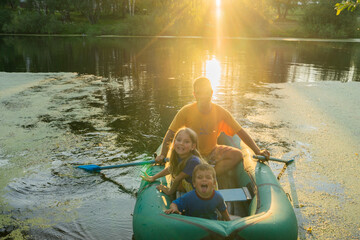 family rides in a rubber boat on the lake, boy and girl with dad, dad with daughter and son, sunset