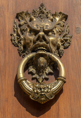 Devil head door knocker on an old door. 
