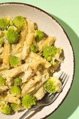 Roman cauliflower, Broccolo Romanesco, Romanesque cauliflower penne pasta with cauliflower cream. A vegetarian version of the famous spring Roman pasta. Top view, green background, spring, close up