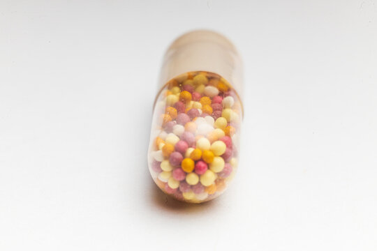 Close up picture of Coloured capsules , pills and tablets against a white background.