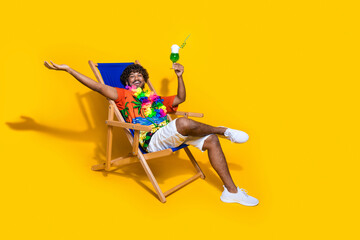 Photo of nice man wear print hawaii shirt enjoy drink palm show empty space relaxing on deckchair...