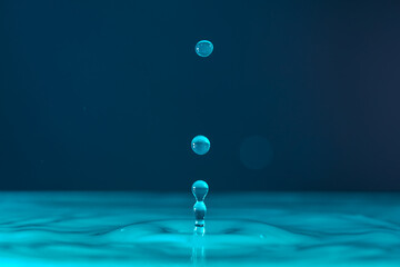Water droplets fall down closely into the dark blue water, making it the perfect center in nature