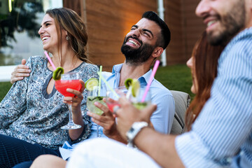 Laughing friends with cocktails - joyful garden mingle, refreshing drinks - young people happy...