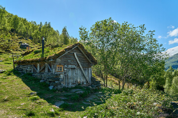 Fototapeta na wymiar old hut along the hiking trail towards the spectacular Seven Sisters waterfall through deep green forest along the Geirangerfjord, Norway on a sunny day.