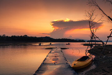Sunset view of the Kaeng Krachan reservoir with fishing boat and tourist rowing canoe