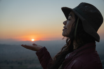 mexican young girl in a mountain in the sunset "holding" the sun in her hand