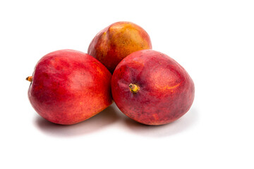 three ripe natural looking mangoes on a white table top