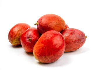 a pile of ripe natural looking red mangoes on a white table top isolated on white