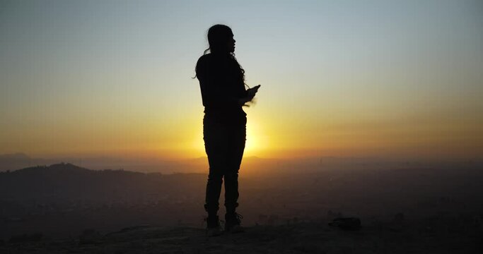 Silhouette of youn mexican girl moving her body in the sunset, in a mountain