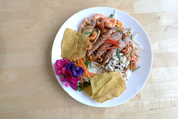 Pad Thai or Thai stir-fried noodles with shrimp and crayfish in white dish on table