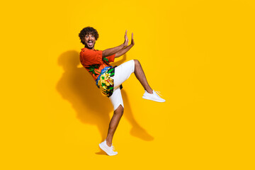 Full length photo of crazy guy wear hawaii print shirt pushing imaginary object to empty space isolated on yellow color background
