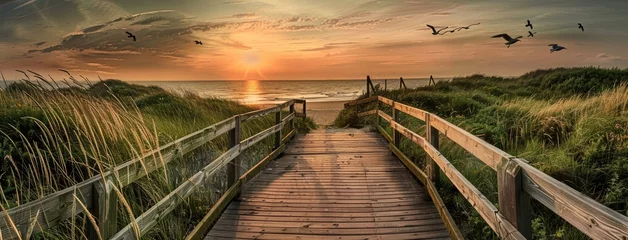 Photo sur Aluminium brossé Descente vers la plage a wooden boardwalk leading to the sea at sunset, offering a mesmerizing panoramic view of dunes, grassland landscape, and seagulls soaring against a stunning sky.