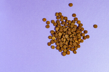 Handful of dry food cat food. Love to the animals. Care, Love. Purple background.
