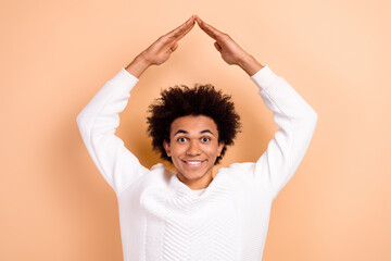 Photo of positive young man dressed white jumper hands above head showing roof safety protection...