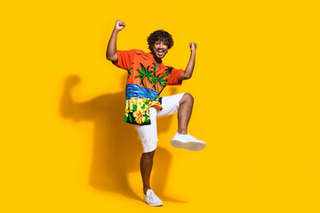 Fototapeta na wymiar Full size photo of satisfied man dressed print shirt white shorts clenching fists win lottery yell isolated on yellow color background
