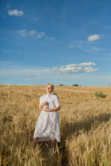 women in a white dress standing at the field of wheat