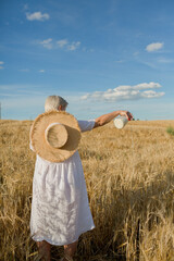 women in a white dress standing at the field of wheat