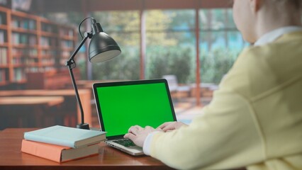 A laptop with a green screen chroma key on the library table. Advertising area, workspace mock up.