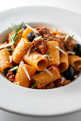 Piatto di deliziosi rigatoni conditi con sugo di salsiccia e olive nere, pasta italiana, cibo...