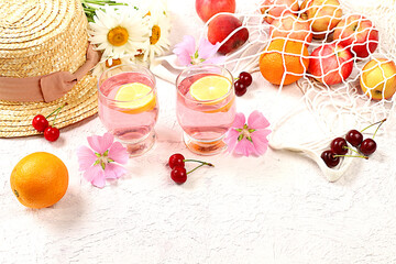 Summer fashion banner on a bright background. Straw hat, fruits in an eco-bag, refreshing alcoholic...